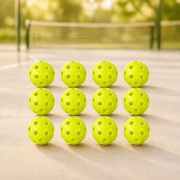 A standard perforated plastic pickleball ball resting on a hard court surface.